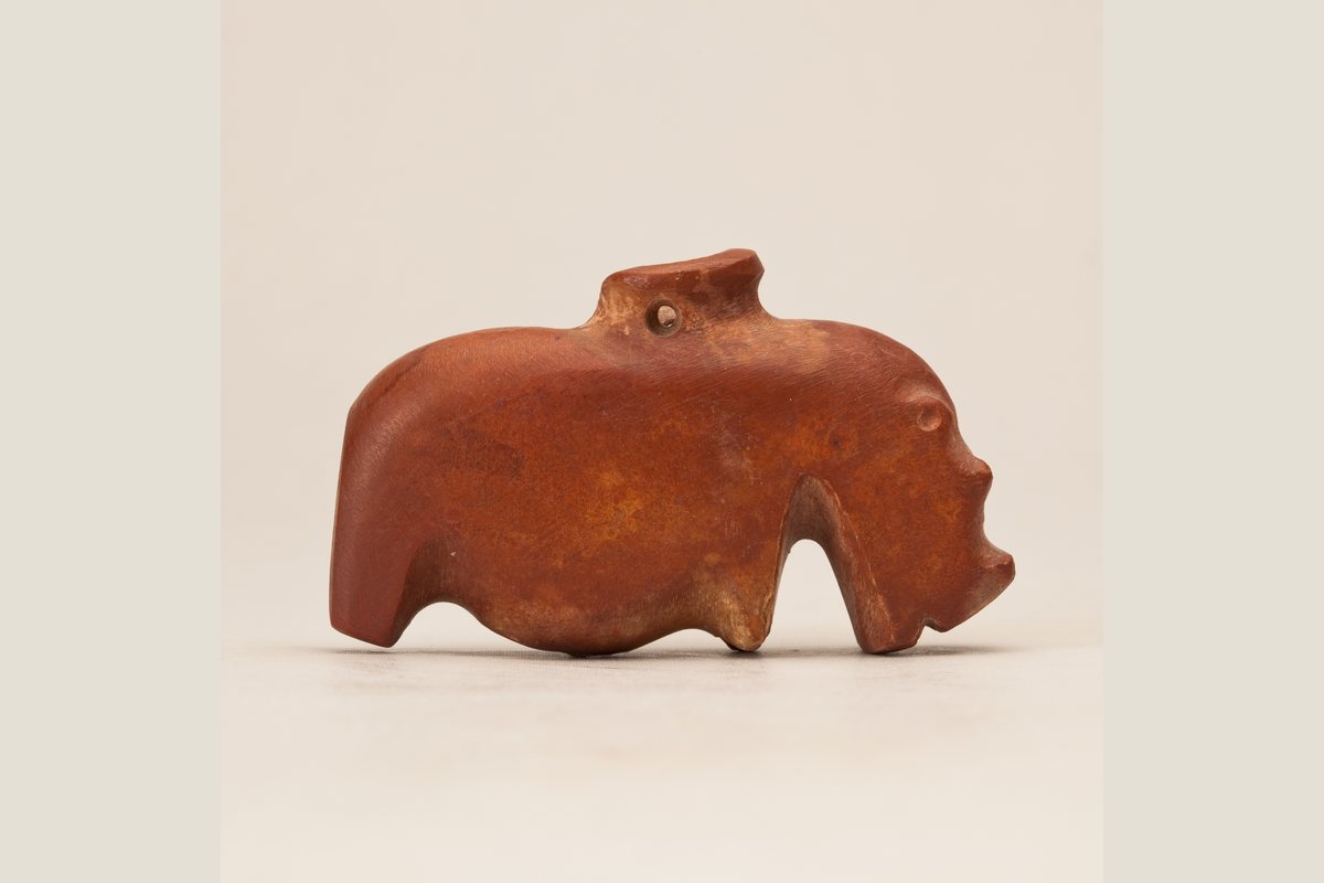 Small ancient Egyptian hippopotamus amulet photographed against a neutral background